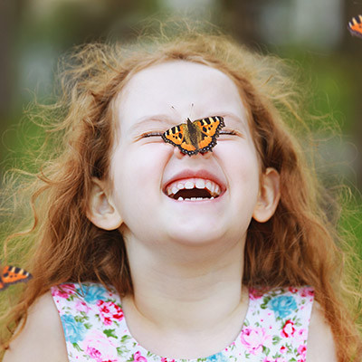 Enfant souriant et amusé par un papillon posé sur son nez